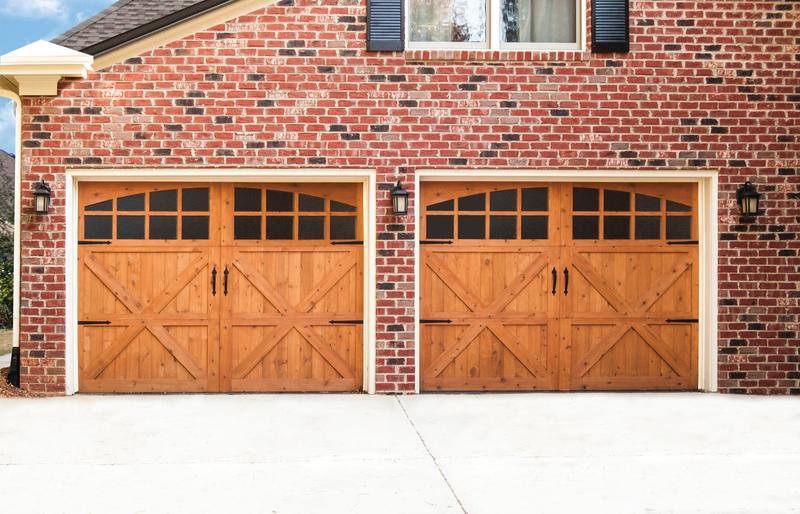 Light wood carriage door, X braces, arched windows, two single doors, in a brick wall