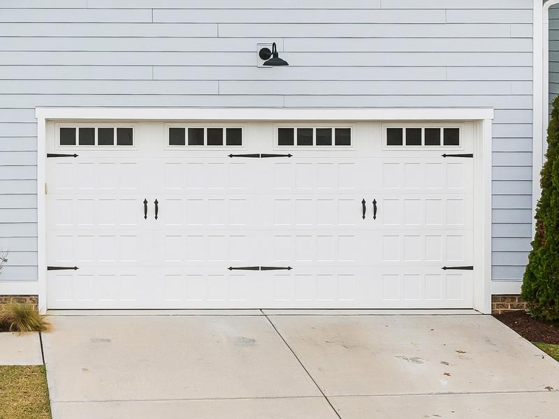 White raised panel door, top windows, black handles, double door, in a board-and-batten wall