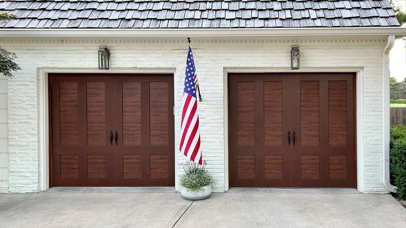 Dark wood carriage door, tall panels, black handles, two single doors, in a painted brick wall