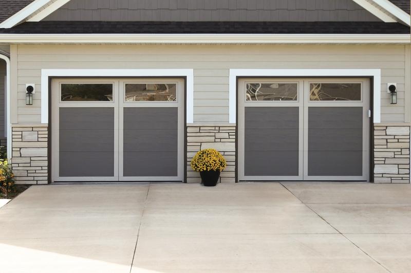 Gray carriage door, vertical boards, square windows, two single doors, in a lap siding wall