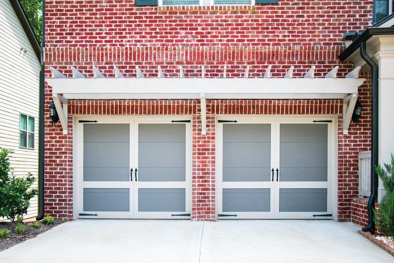 Gray carriage door, tall panels, black handles, two single doors, in a brick wall