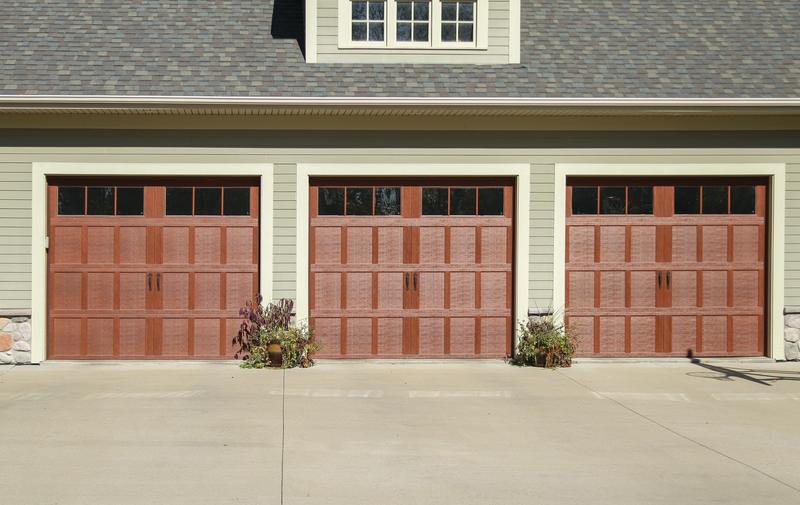 Medium wood carriage door, square windows, black handles, three single doors, in a lap siding wall