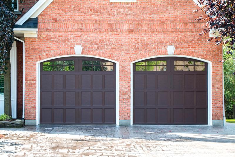 Brown shaker door, recessed panels, arched windows, two single doors, in a brick wall