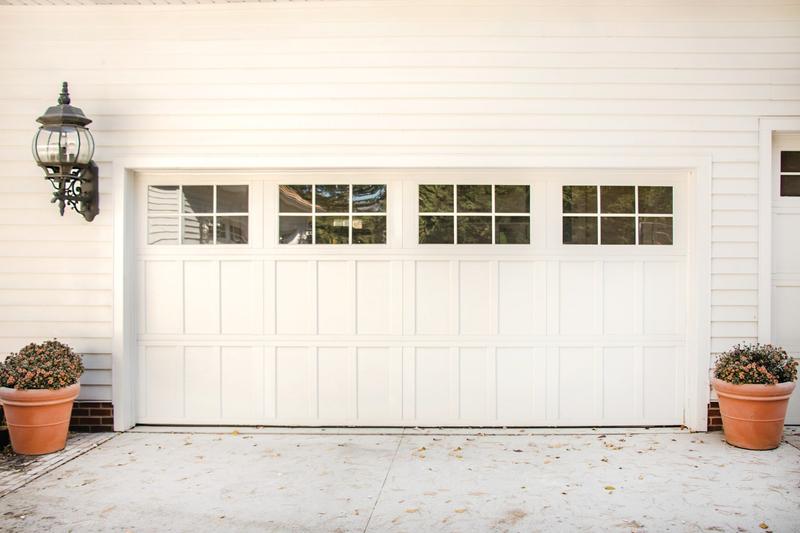 White carriage door, tall panels, square windows, double door, in a lap siding wall