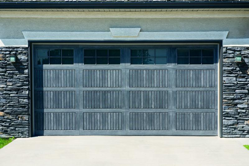 Charcoal raised panel door, grooved panels, top windows, double door, in a stone wall