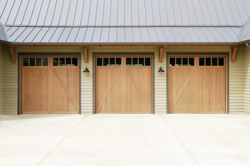 Light wood carriage door, Z brace, square windows, two single doors, in a lap siding wall