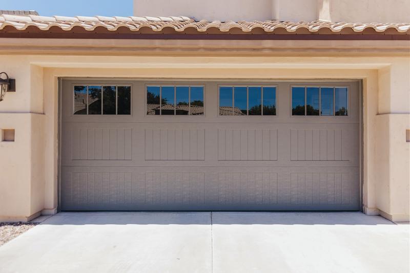 Gray raised panel door, grooved panels, square windows, double door, in a stucco wall