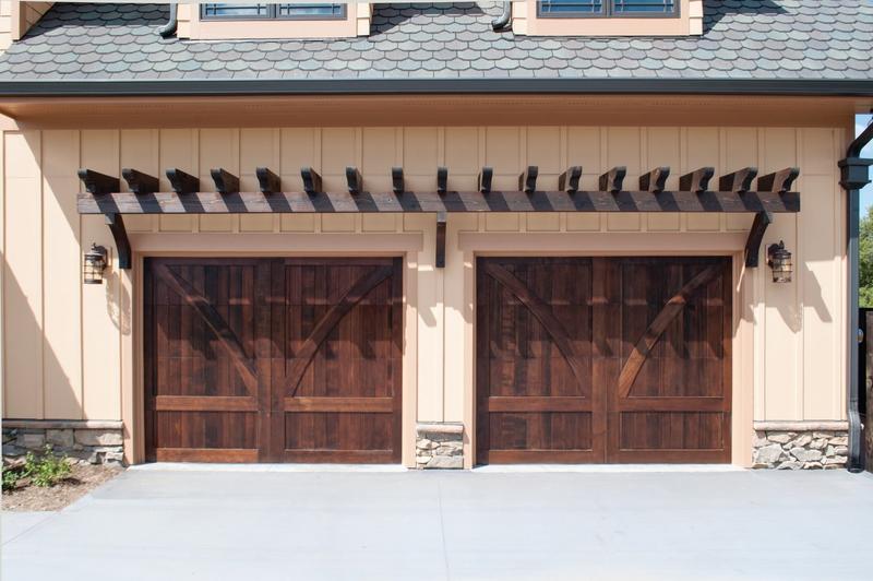 Dark wood carriage door, arched braces, two single doors, in a board siding wall