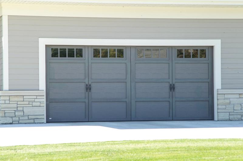 Gray carriage door, tall panels, square windows, double door, in a stone wall