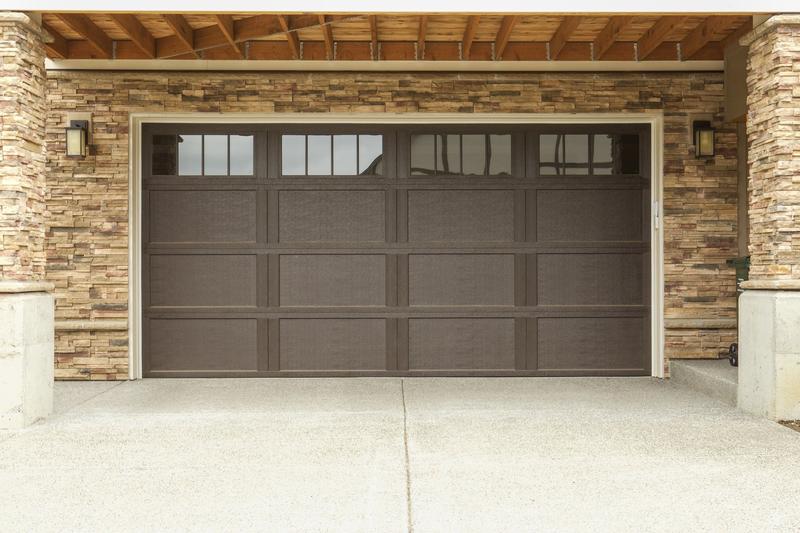 Brown carriage door, tall panels, square windows, double door, in a stone wall