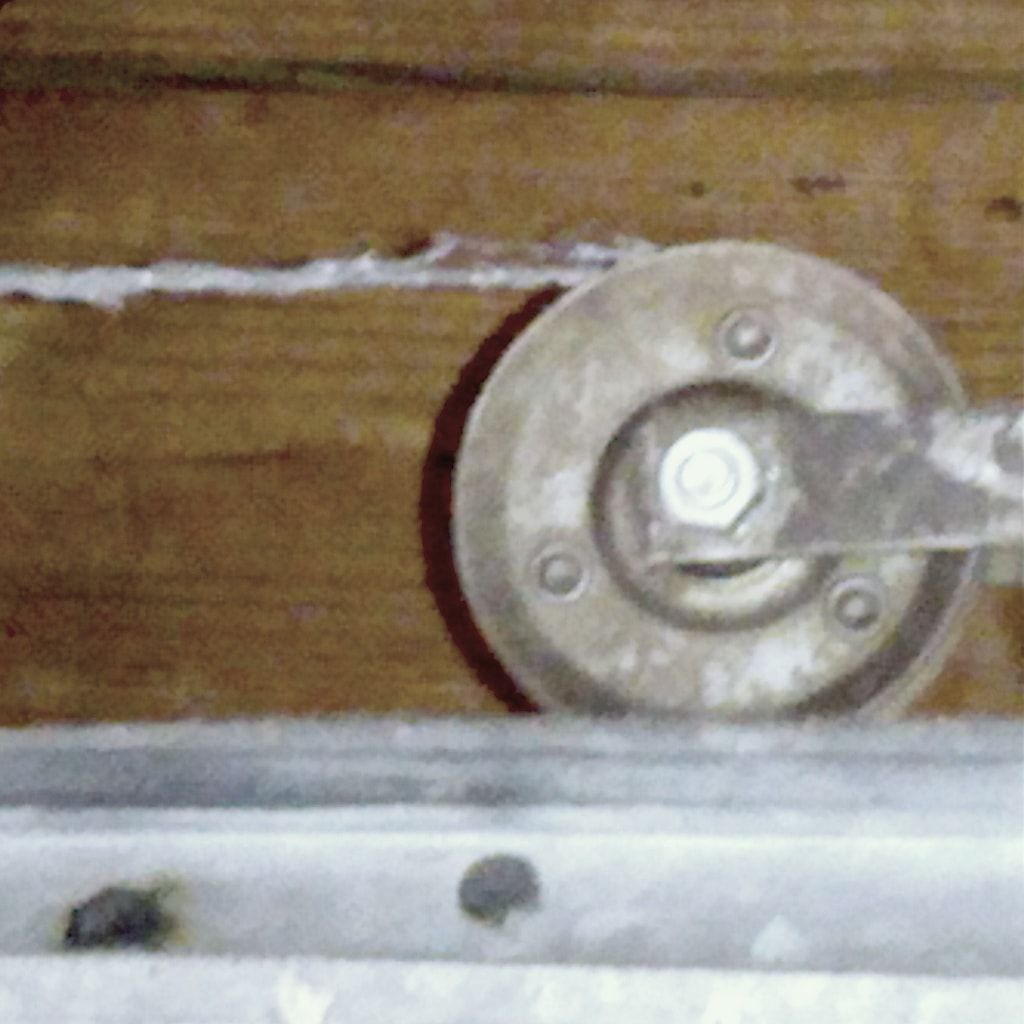A frayed garage door lift cable running onto its pulley