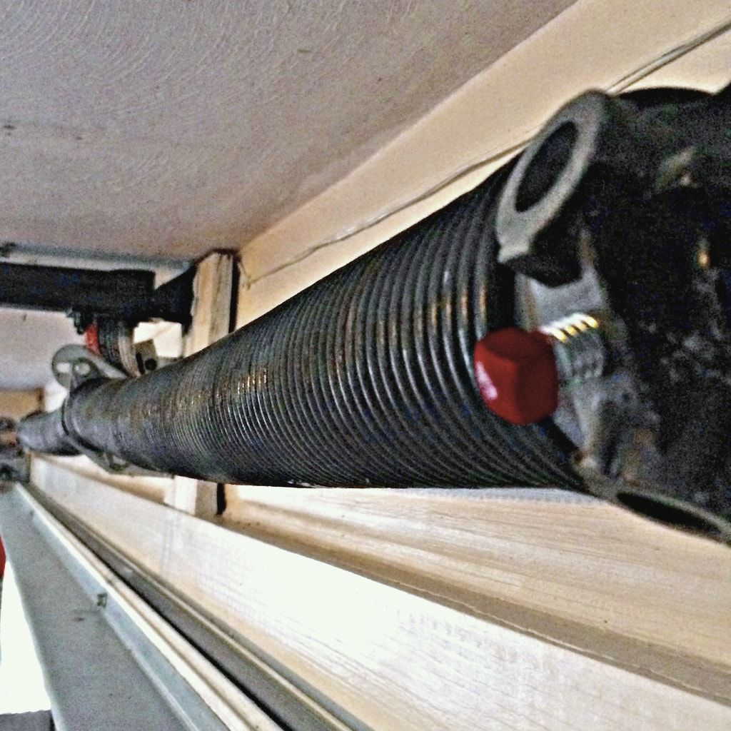 A garage door torsion spring on its shaft above the door