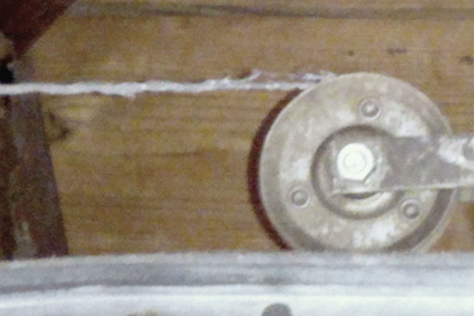 A frayed garage door lift cable running onto its pulley