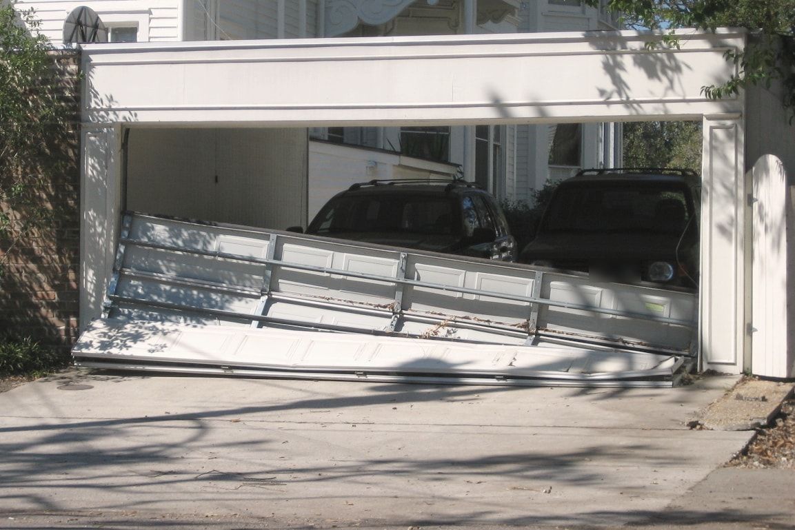 A garage door knocked off its tracks and hanging out of the opening
