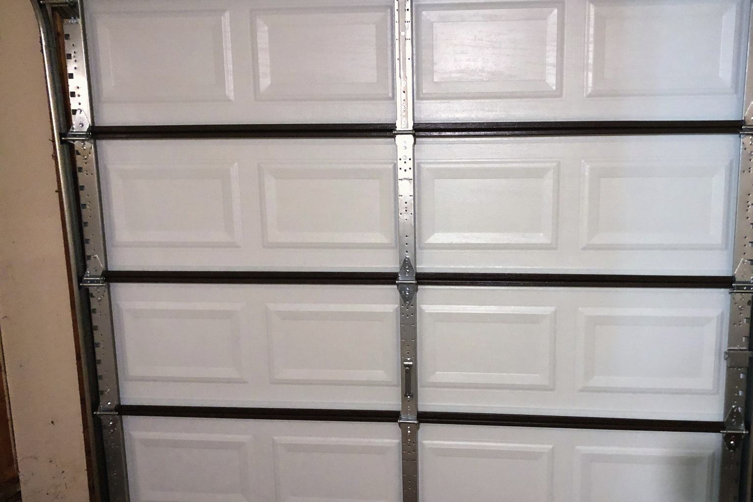 The inside of a garage door with its hinges, rollers and tracks